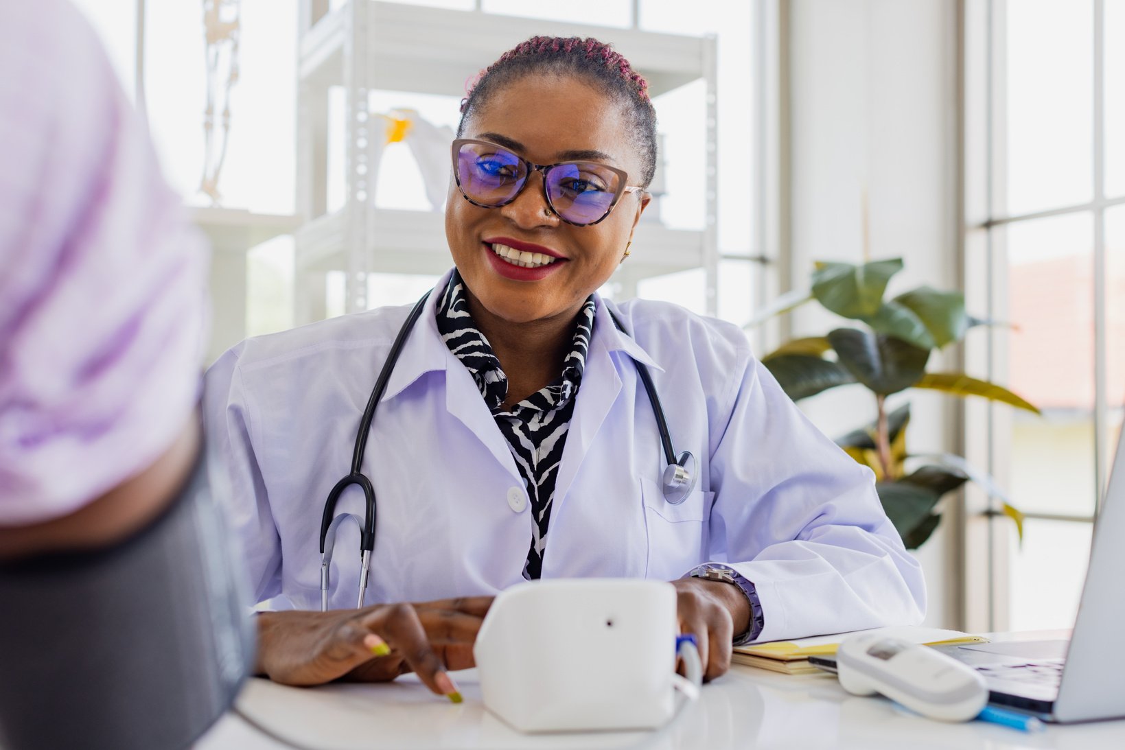 Black doctor with patient in doctor office.